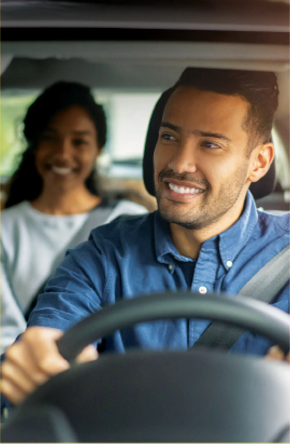 Um homem sentado no banco do motorista e uma mulher sentada no banco de tras.